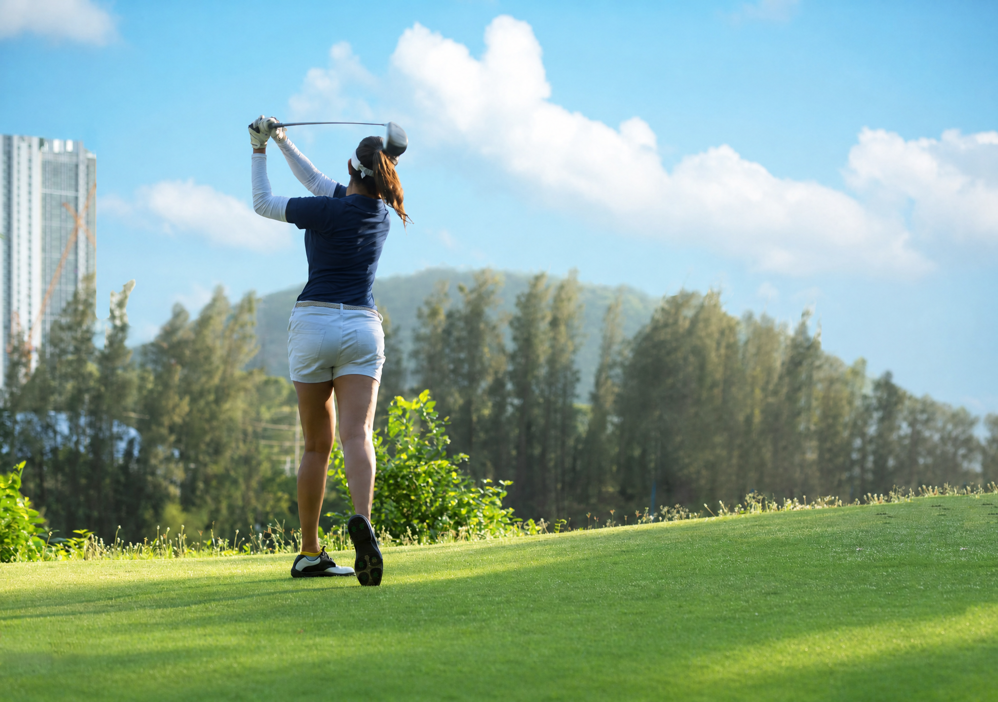A golfer follows through on a sunlit fairway