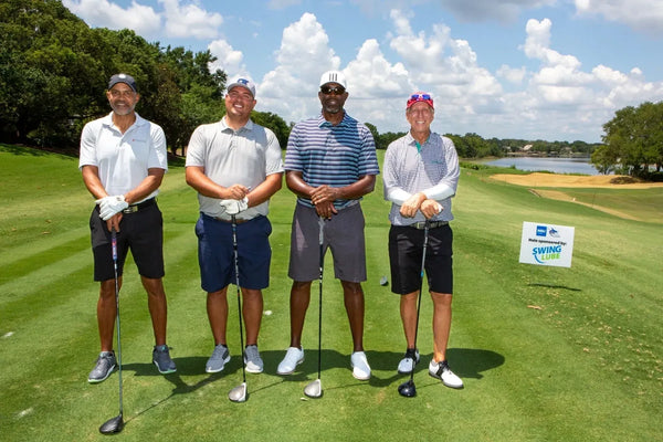 Four golfers with their drivers at the tournament